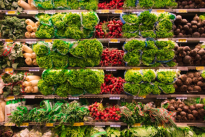 Fresh leafy greens and root vegetables neatly arranged on grocery store shelves