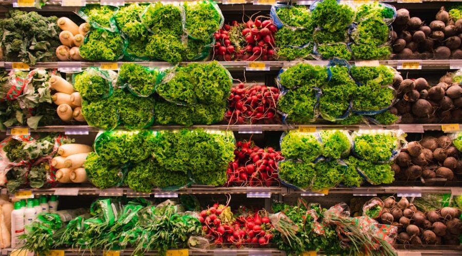 Fresh leafy greens and root vegetables neatly arranged on grocery store shelves