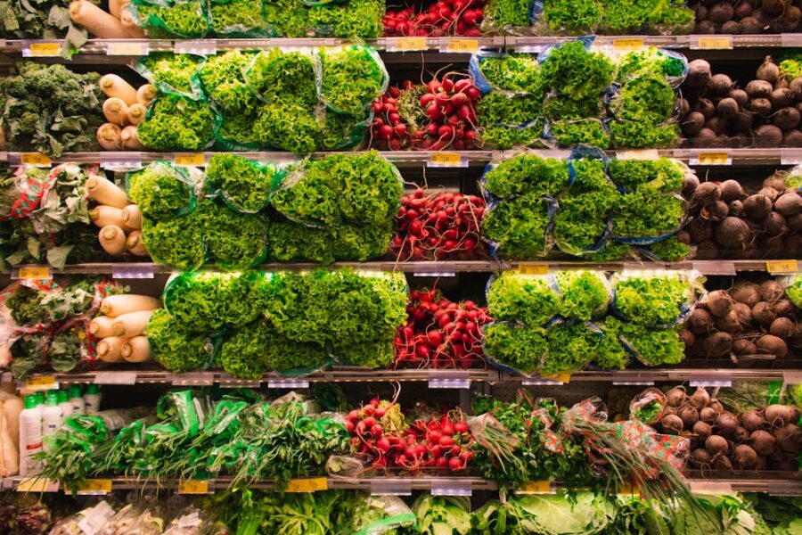 Fresh leafy greens and root vegetables neatly arranged on grocery store shelves